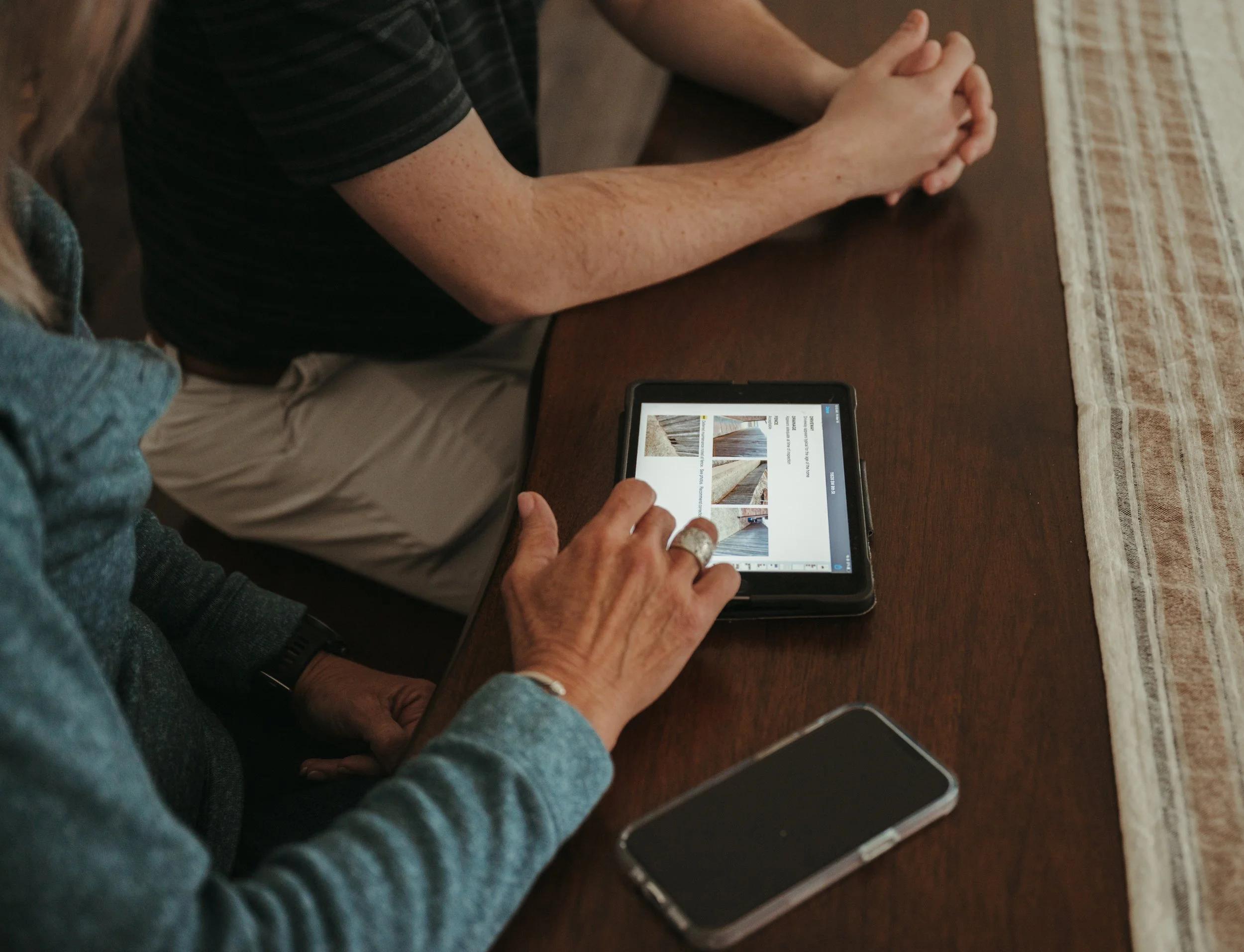 Homeowner reviewing a photo inspection report on a tablet at a Boerne kitchen table