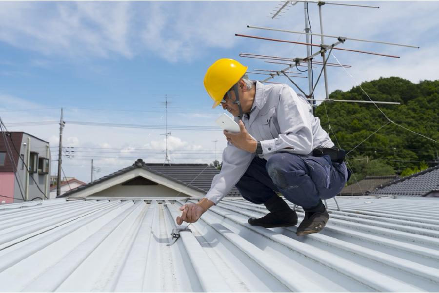 Inspector checking exposed fasteners on a metal roof in Boerne