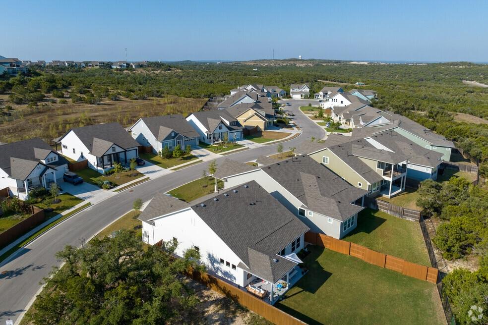 Side-by-side of a standing seam metal roof and a shingle roof on neighboring Hill Country homes