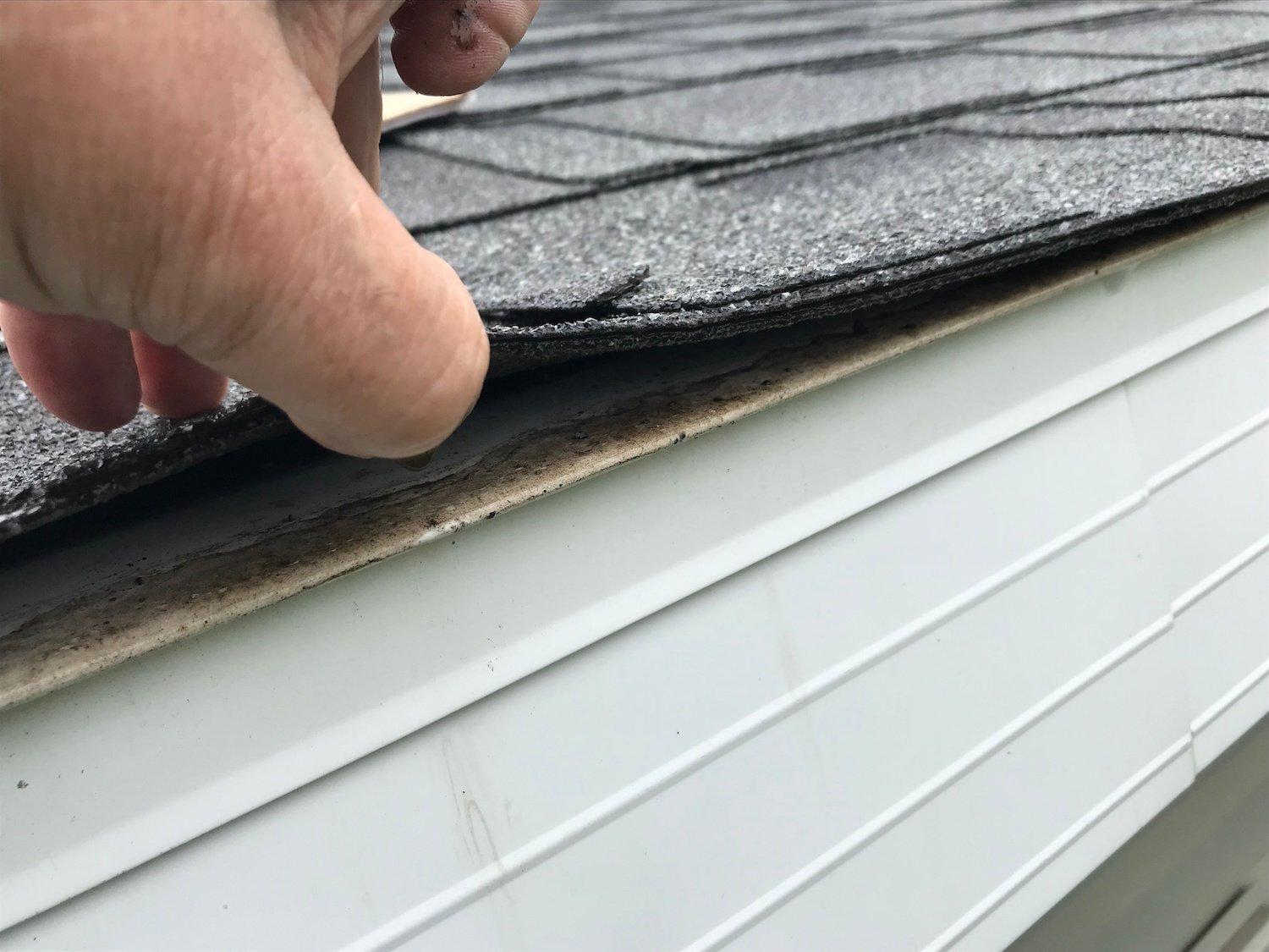 Wind-creased shingles along a rake edge on a Helotes home